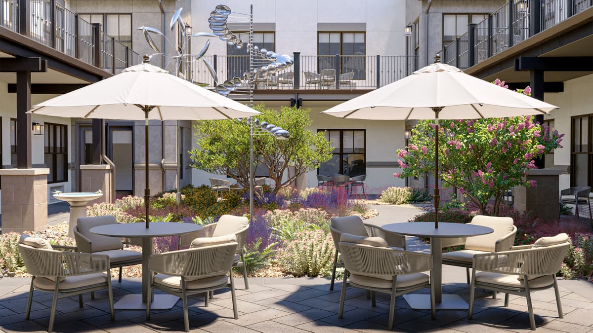Rendering of a landscaped courtyard with umbrella seating at a seniors community