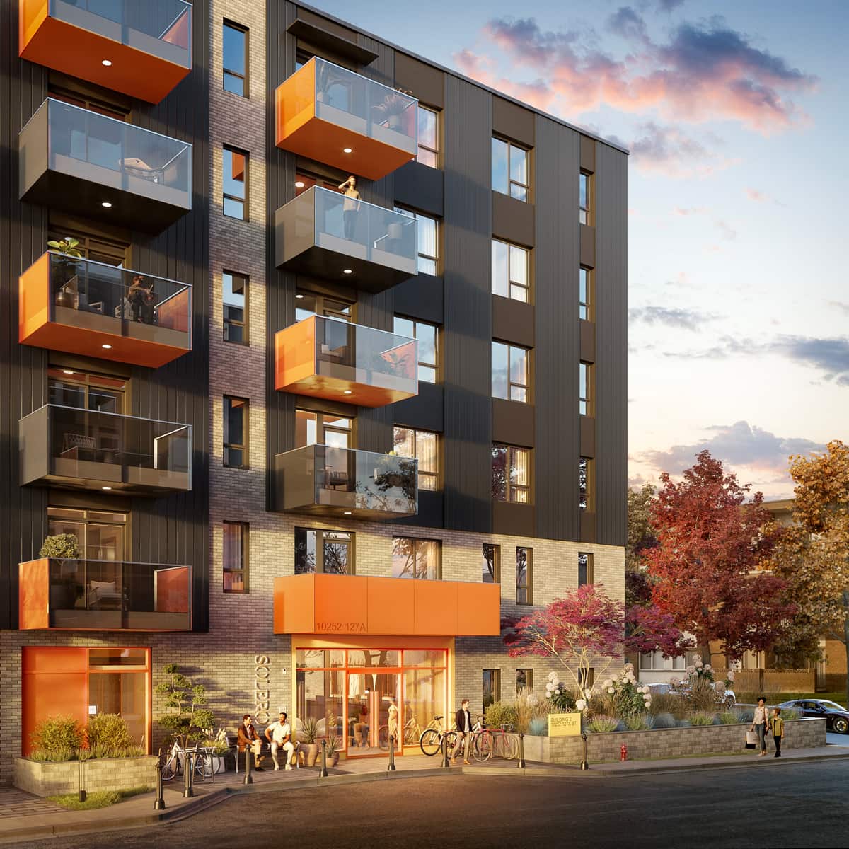 Dusk rendering of the entrance to a mid-rise multifamily building with orange balcony accents
